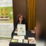 Paola Neglia al banchetto firma libro con il logo della Convention Er-Etici a Milano